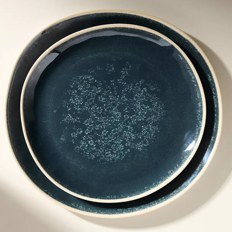 Two dark blue ceramic plates with a subtle speckled pattern are stacked together, showcasing a glossy finish.