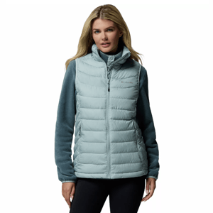 A woman is wearing a Columbia insulated vest in a light blue color over a dark blue long-sleeve shirt.