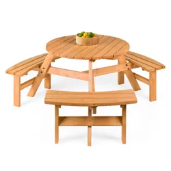 A round wooden picnic table with attached curved benches, topped with a bowl of assorted citrus fruits.