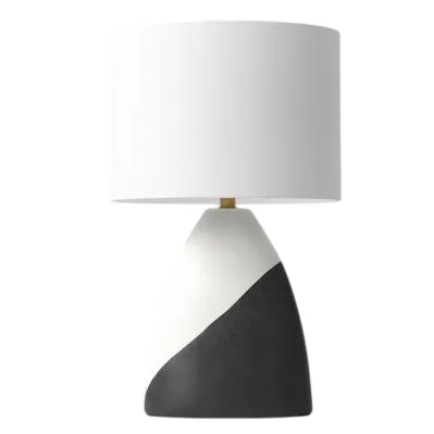 A modern table lamp with a white cylindrical shade and a two-toned base featuring white and dark gray angled sections.