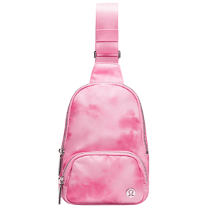 A small pink sling bag with a tie-dye pattern, featuring a front zippered pocket and an adjustable strap. The brand logo is visible on the front of the bag.