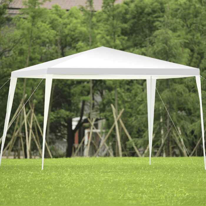 A white outdoor canopy tent with four legs and a peaked roof set on a grassy area, supported by ropes for stability.