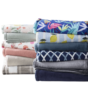 A variety of folded blankets in different colors and patterns, including floral, fruit, and geometric designs, stacked on a surface.