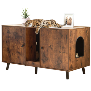 A wooden cabinet with a cat doorway is shown, featuring two doors and a shelf inside. A cat lies on top alongside a small potted plant and a framed photo.