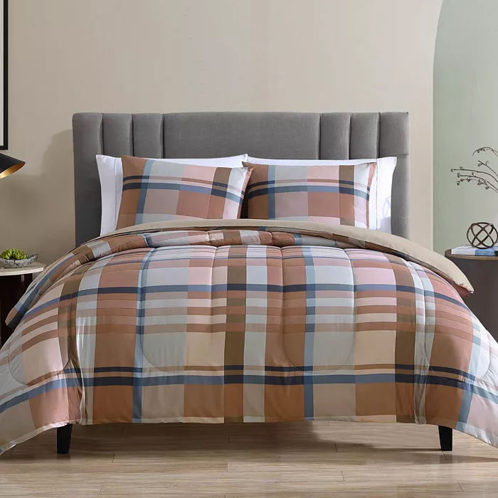 A bed features a plaid patterned comforter set in shades of beige, blue, and brown with matching pillow shams on a gray upholstered headboard.