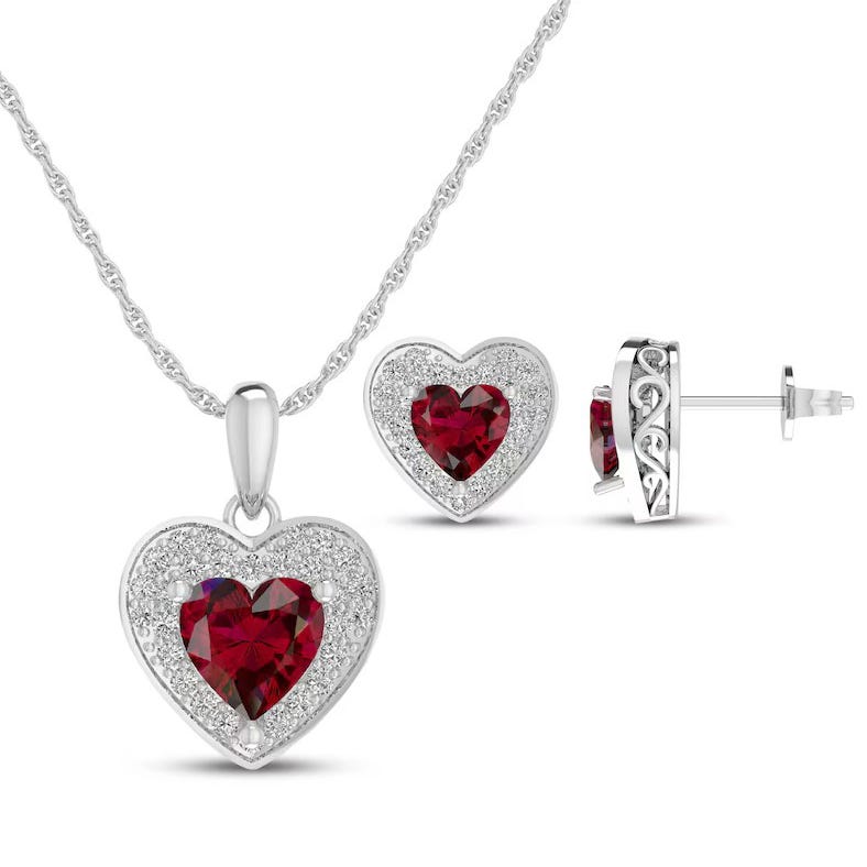 Silver jewelry set featuring a heart-shaped pendant necklace and earrings, each with a dark red gemstone center surrounded by small clear stones.