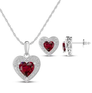 Silver jewelry set featuring a heart-shaped pendant necklace and earrings, each with a dark red gemstone center surrounded by small clear stones.