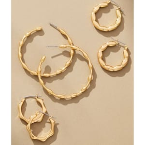 Gold-tone hoop earrings with textured designs in varying sizes are displayed on a neutral background.
