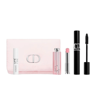 A cosmetic set includes a white serum bottle, pink lip balm, black mascara, and a light pink pouch with a metallic clasp.