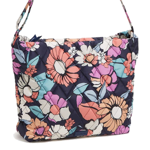 A colorful quilted shoulder bag with a floral pattern featuring large flowers in pink, orange, blue, and white on a dark background.