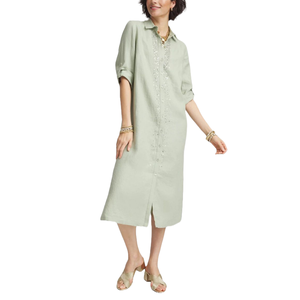 A light green linen midi shirt dress with subtle embellishments on the front, featuring a collared neckline and button-down closure. The dress has rolled-up sleeves and a front slit, paired with heeled sandals and gold jewelry.