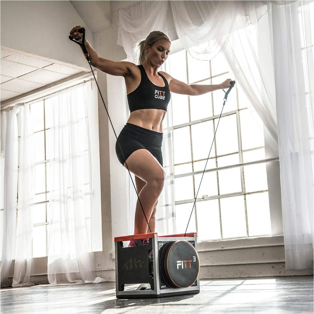A woman is using a compact, multifunctional fitness device for resistance training.