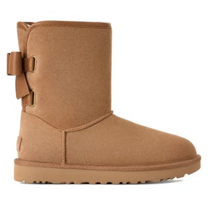 Tan suede boot with a side bow detail, featuring a flat sole and mid-calf height.