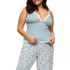 Plus-size pajama set includes a light blue cami with lace trim and a bow accent, paired with loose-fitting pants featuring a colorful floral pattern.