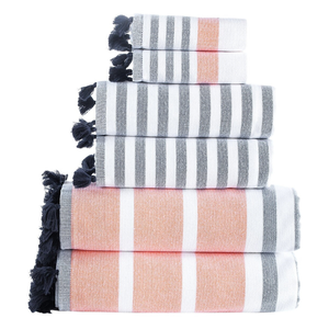 A stack of striped towels with tassel edges in black, white, and orange colors, arranged in descending size order.