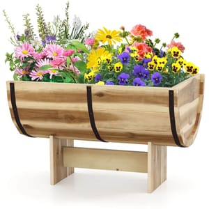 Wooden raised garden bed with metal accents, containing various colorful flowers, including pink daisies, yellow blooms, and purple violas.