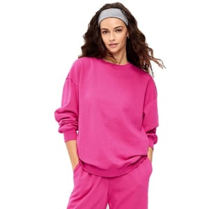 A person is wearing a bright pink sweatshirt and matching pants. They also have a gray headband in their hair.