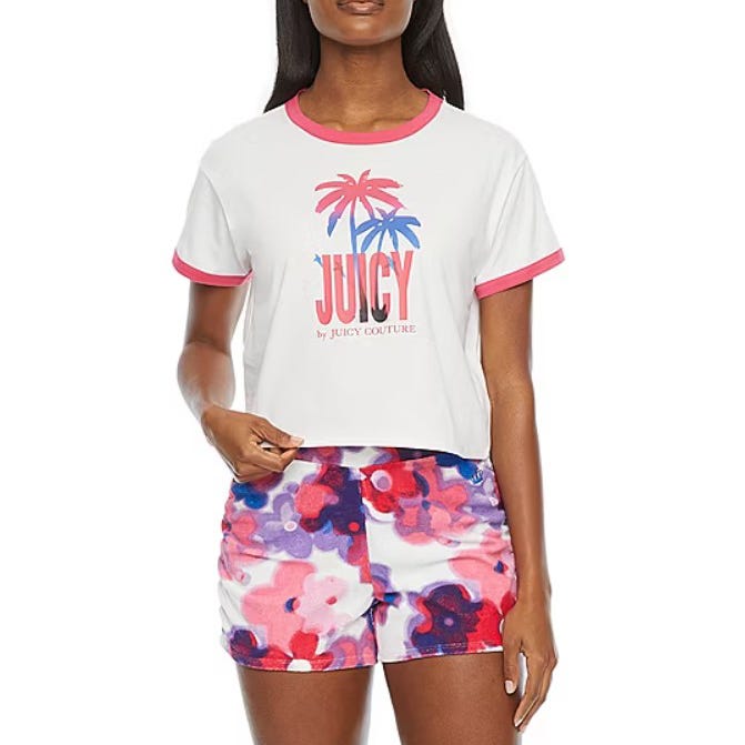 A woman is wearing a white T-shirt with a pink trimmed collar, the word \“JUICY,\“ and a palm tree graphic, along with multicolored floral print shorts.