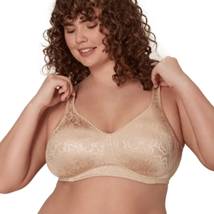 A woman wearing a nude-colored, patterned wireless bra is adjusting the straps.