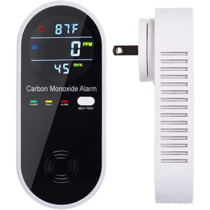A digital carbon monoxide alarm displays temperature, CO levels in PPM, and relative humidity. The device features power, fault, and alarm indicators, a self-test button, and side ventilation.