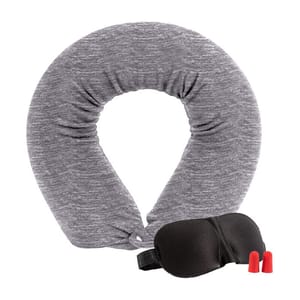 A gray, soft travel neck pillow is shaped like a horseshoe, accompanied by a black sleep mask and two red earplugs designed for comfort and noise reduction during travel.