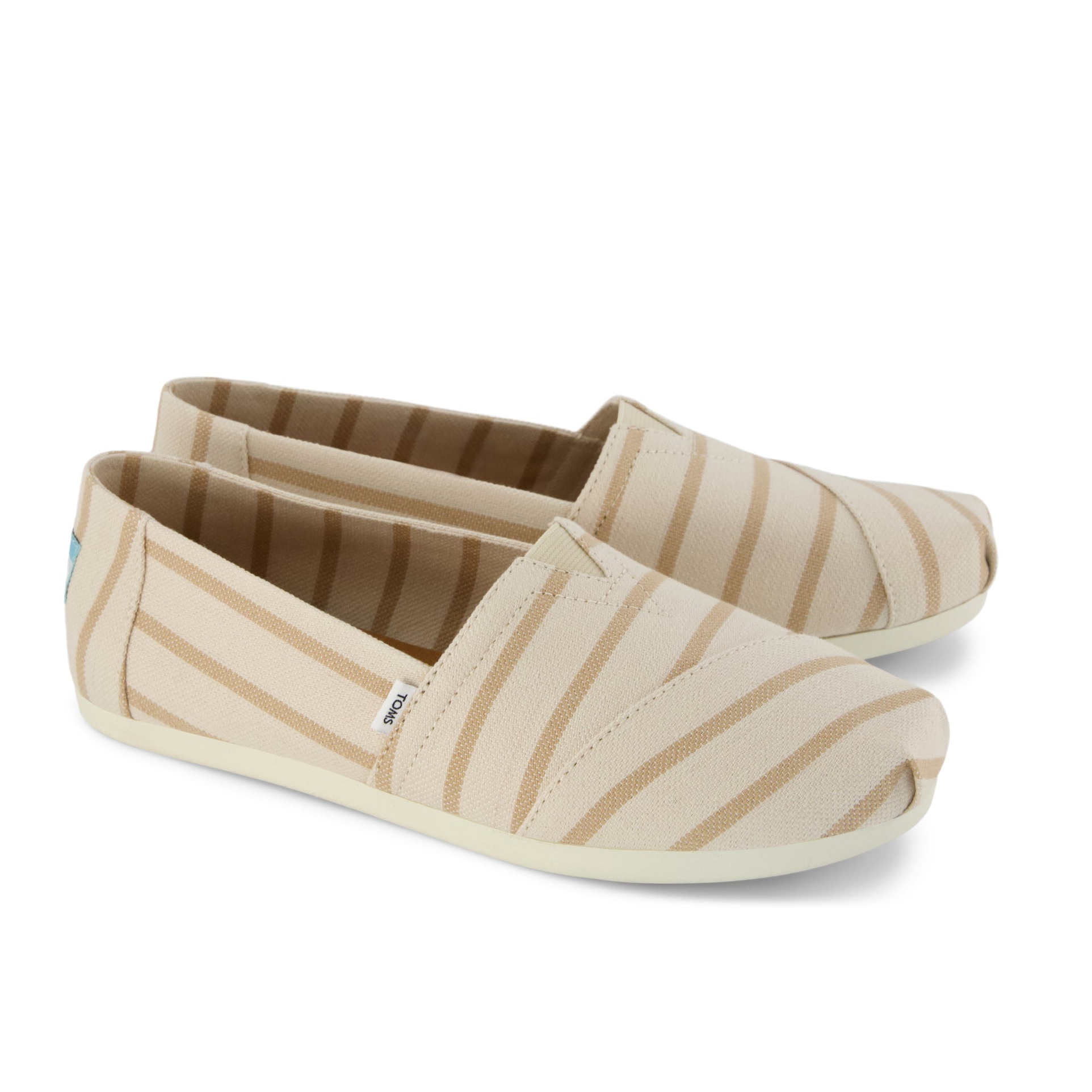 Beige canvas slip-on shoes with tan stripes, featuring a subtle elastic V for easy on and off, and a flat rubber sole.