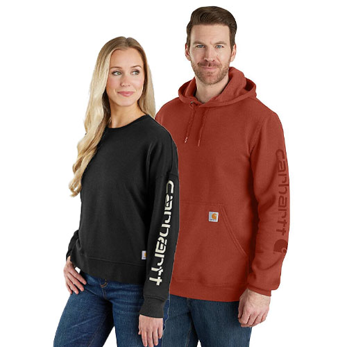 Two people wearing Carhartt clothing: one in a black long-sleeve shirt with \“Carhartt\“ on the sleeve, and the other in a rust-colored hooded sweatshirt with the same branding on the sleeve and a small logo patch.