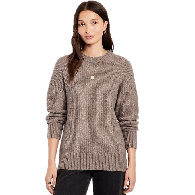 A woman is wearing a taupe ribbed sweater with long sleeves and a round neckline, paired with dark pants.