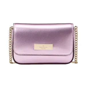 A metallic pink leather crossbody bag with a gold chain strap and a rectangular logo plaque on the front.