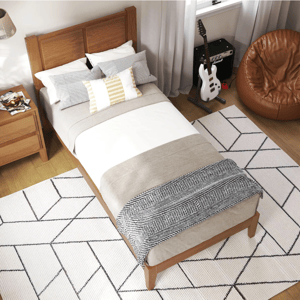 A cozy bedroom setup with a wooden bed frame, layered bedding, and several decorative pillows. Nearby, a guitar and amp are placed alongside a leather bean bag chair, and geometric-patterned rugs cover the floor.