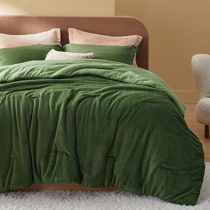 A plush green comforter set with three pillows in varying shades of green and pink, on a bed with a brown headboard.