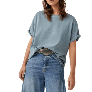 A person is wearing a loose, light blue rolled-sleeve t-shirt with high-waisted, wide-leg blue jeans and a large round belt buckle.