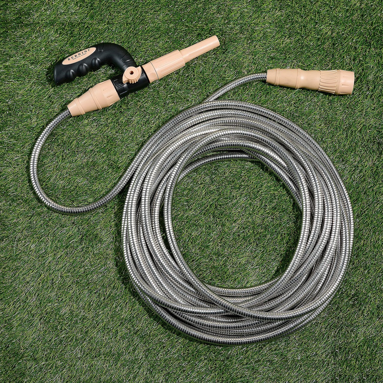 50' expandable metal hose with a durable coiled design, beige nozzle, and black handle for easy grip, suitable for various watering needs on grass or garden areas.
