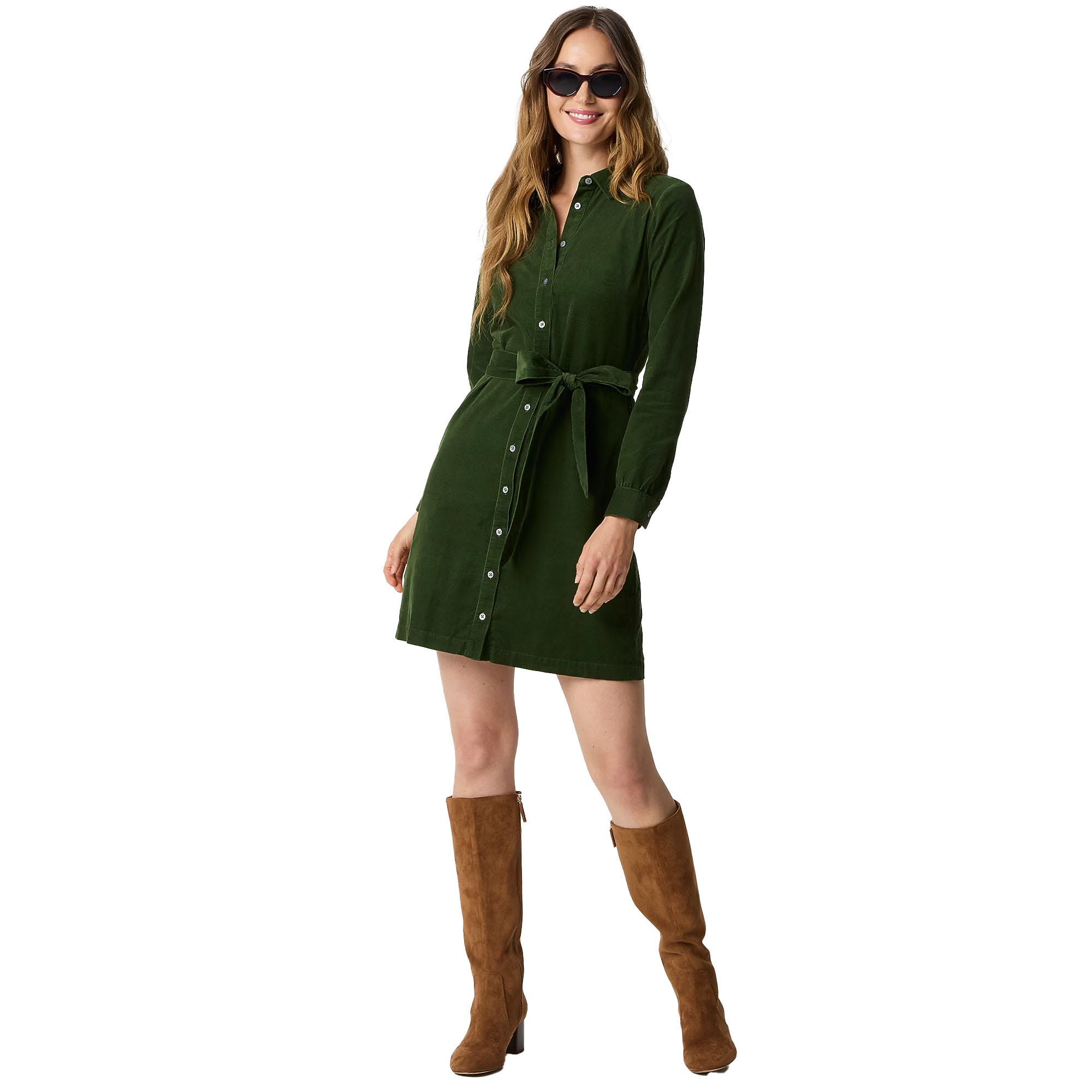 A woman wearing a green button-up shirt dress with a tie belt, paired with knee-high brown suede boots and sunglasses.