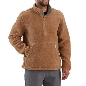 A brown sherpa fleece pullover with a quarter-zip design and a large front pocket, worn by a man with his hands in his pockets.