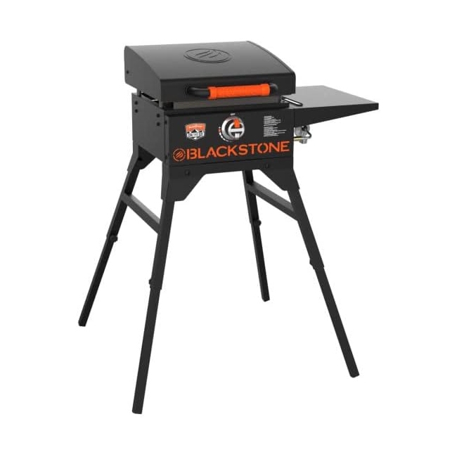Blackstone 17\“ Griddle Bundle includes a portable griddle with a black design featuring an orange handle, collapsible legs, and a side shelf. Ideal for outdoor cooking.