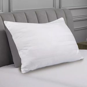 White cotton pillow with a striped pattern, resting on a light gray upholstered headboard.