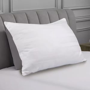 White cotton pillow with a striped pattern, resting on a light gray upholstered headboard.