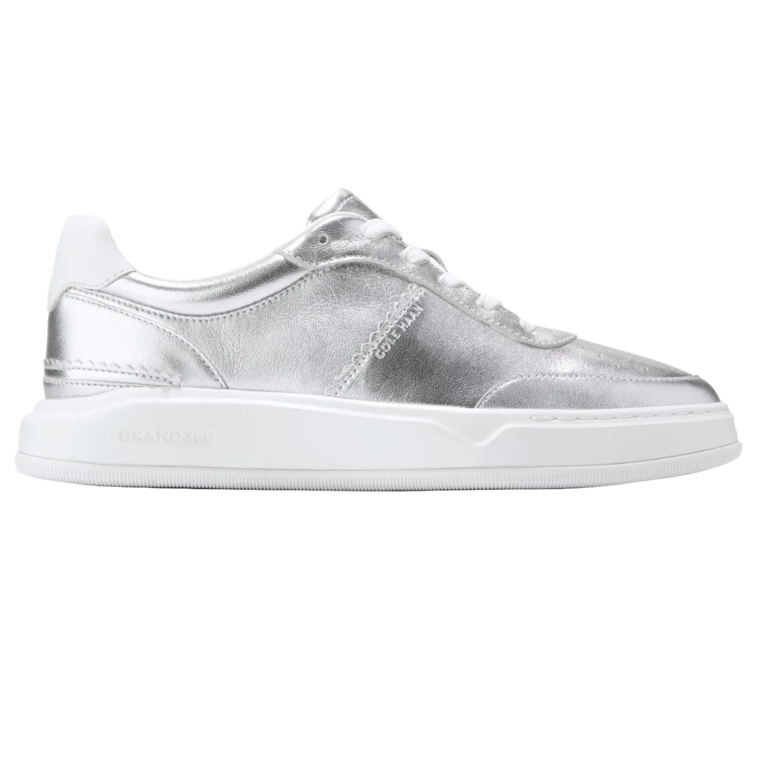 Cole Haan GrandPro Carissa Sneakers feature a sleek design with a metallic silver leather upper and white sole, offering a modern and stylish look.