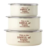 Three stacked, round cream-colored containers with clear lids, featuring the phrase \“This is the SMELL of happy POSSIBILITIES.\“