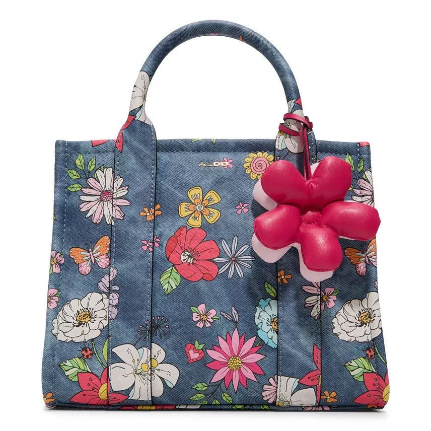 A floral-patterned tote bag with a denim-like texture, featuring a red flower charm hanging from the handle.