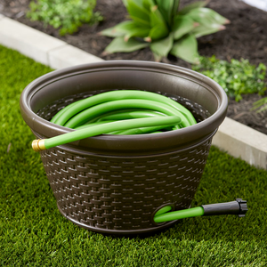 A brown wicker-patterned garden hose storage pot containing a coiled green garden hose.
