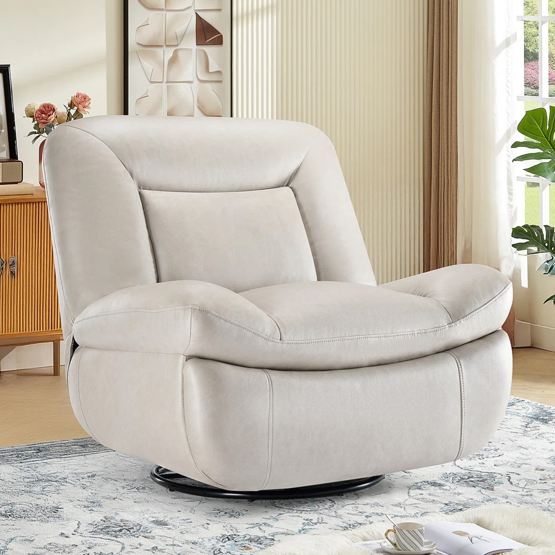 A beige swivel reclining chair with plush cushioning is featured in a cozy living room setting, complemented by a patterned rug and natural light from a large window.
