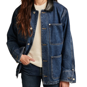 A blue denim field jacket with a black leather collar, featuring button closures and large front pockets, worn over a cream-colored sweater.