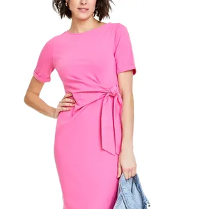 A woman wears a pink dress featuring short sleeves and a side tie detail, while holding a denim jacket.