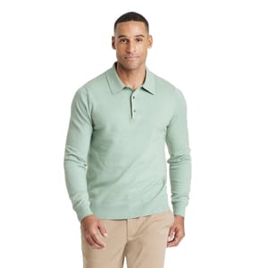A man wears a light green long-sleeve polo shirt paired with beige pants.