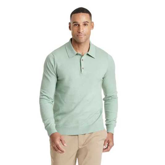 A man wears a light green long-sleeve polo shirt paired with beige pants.