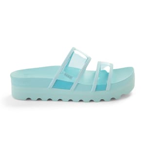 The Reef Vista Hi-Energy Slide Sandals feature a light blue color with transparent straps and a thick, textured sole for added height and grip.