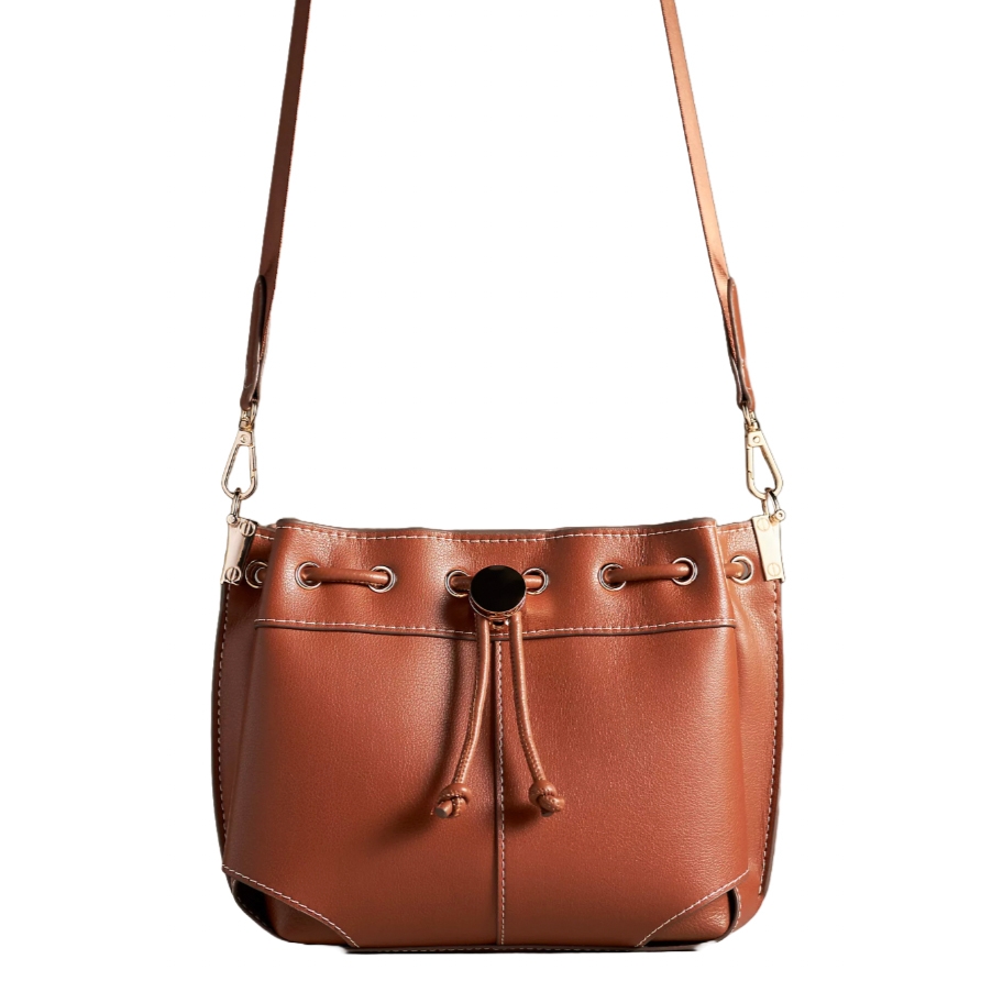 A brown leather crossbody bucket bag with a drawstring closure and metal grommet details, featuring detachable shoulder straps and a simple, elegant design.