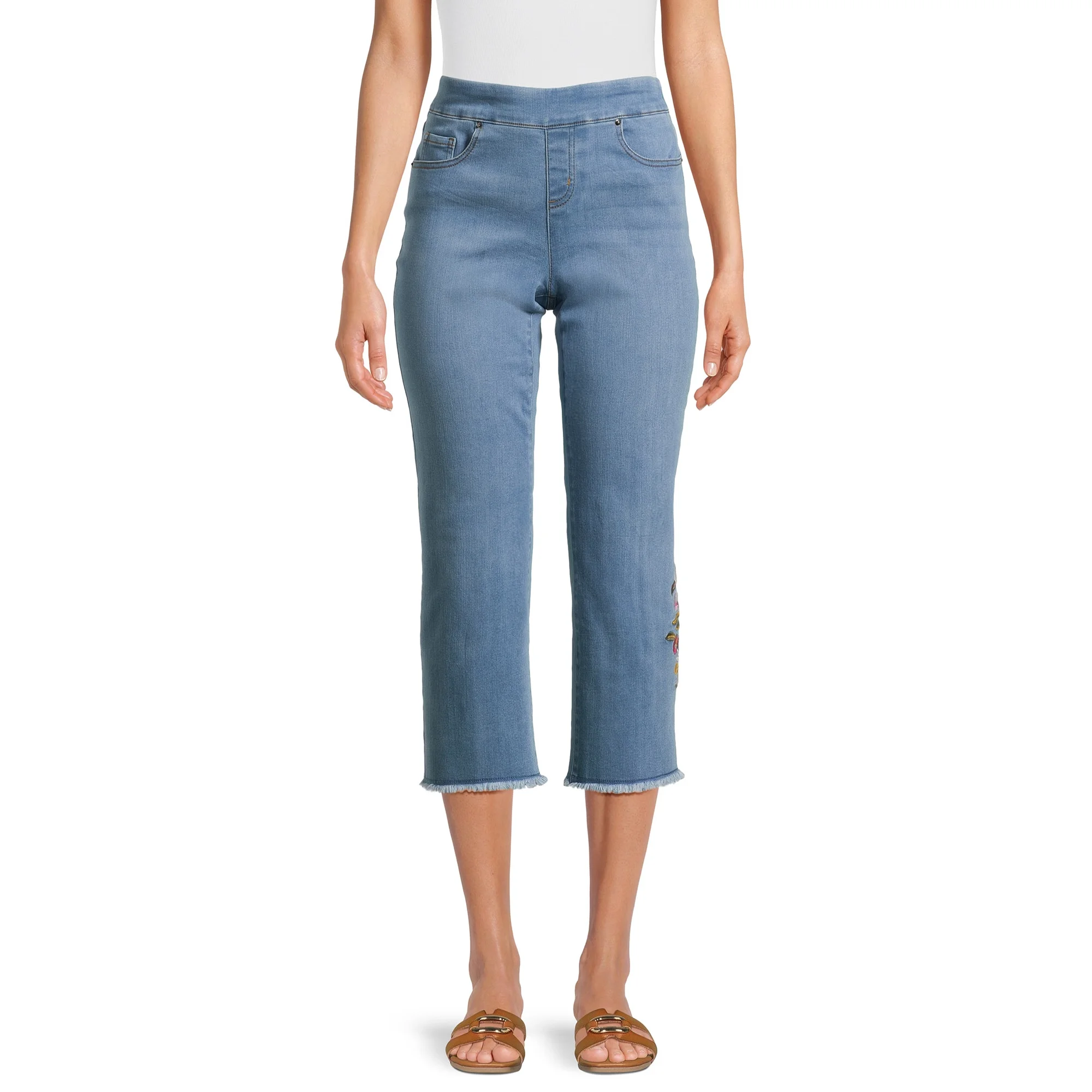 A pair of light blue cropped jeans with frayed hems and brown slide sandals on a person.